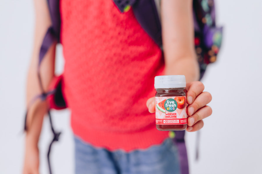 Kind mit Schulranzen präsentiert einen LiveFresh Kids Shot Wassermelone.